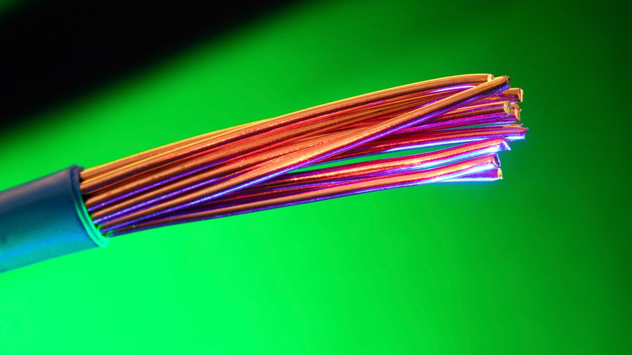 services-01 Close-up of colorful copper electrical wires against a vibrant green backdrop, showcasing vivid contrasts and textures.
